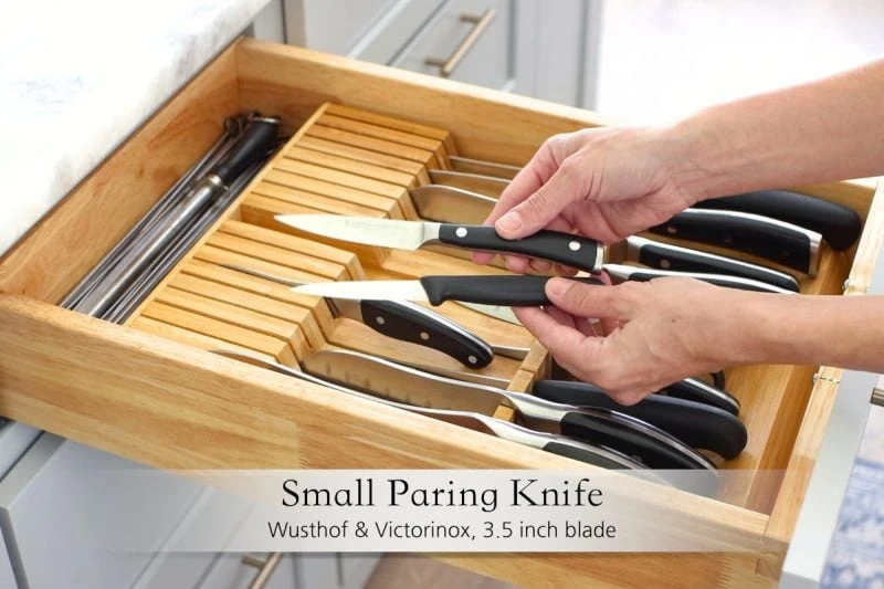 Best kitchen knives - paring knives held over a kitchen drawer with a knife organizer. 