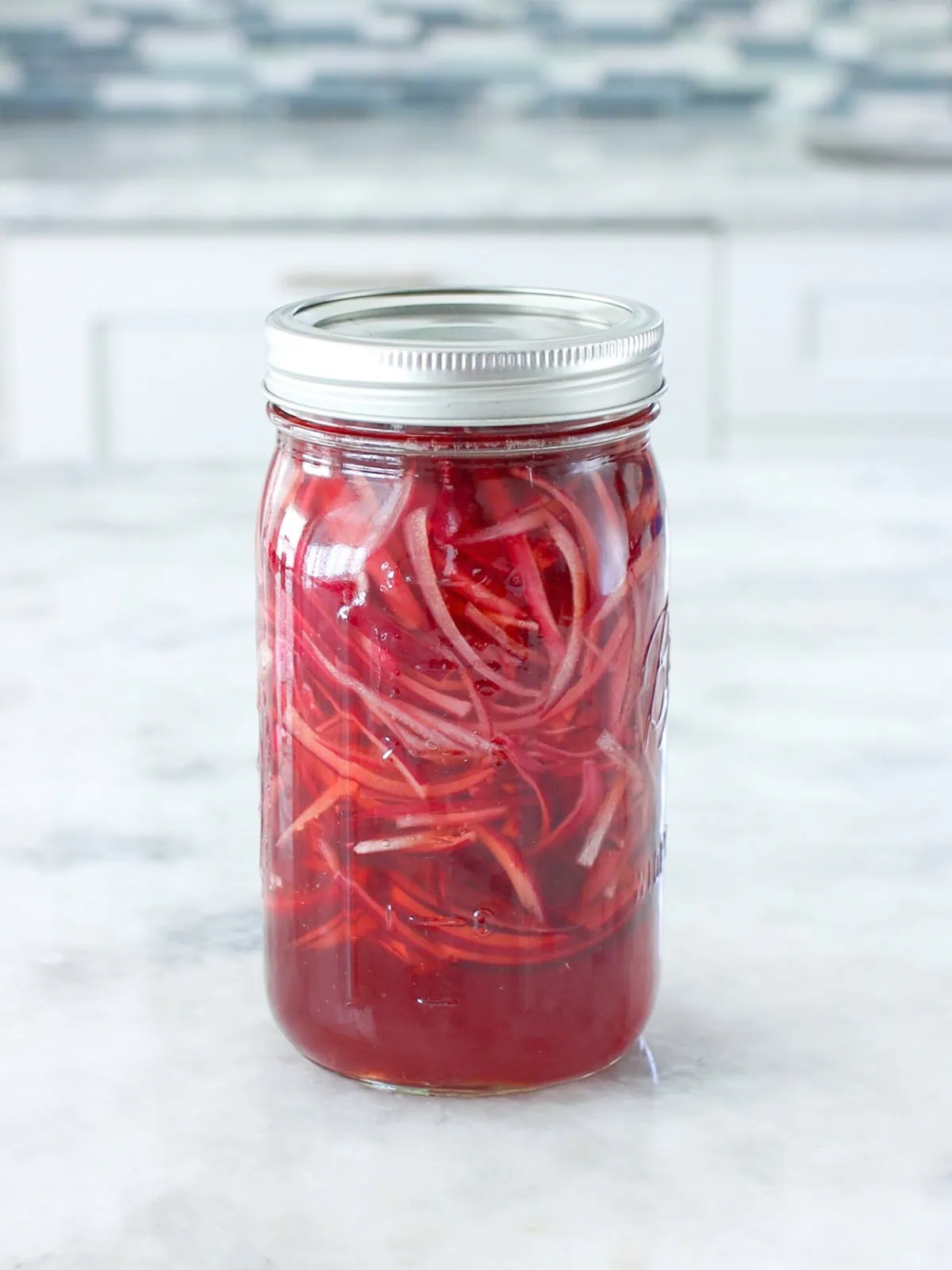 Easy pickled red onions in a glass mason jar on the counter. 